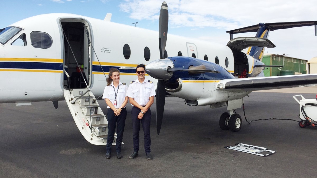 Two pilots standing behind the plane