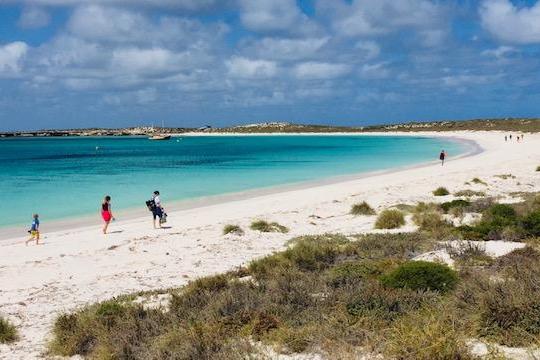Group of people waking on the white sand beach