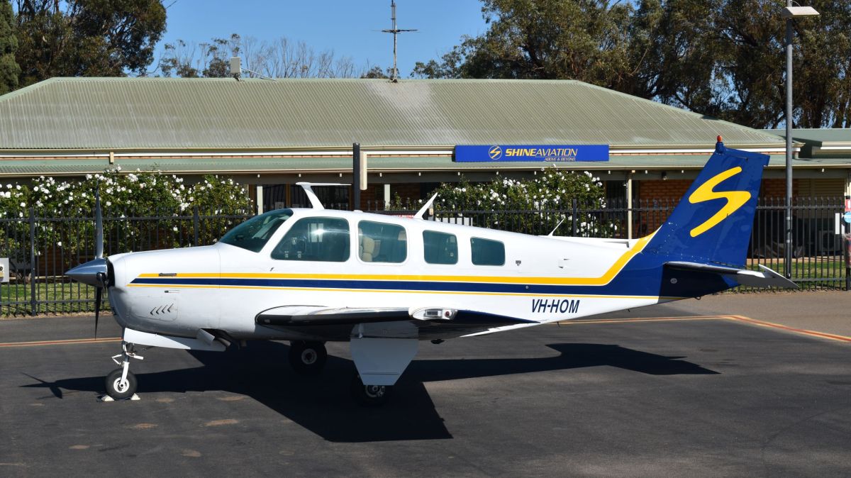 VH-HOM a small airplane is parked on the side of a road